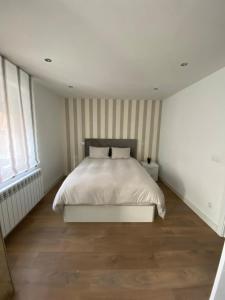 a bedroom with a white bed with striped walls at Alojamiento - Las Murallas de Dulcinea in Avila