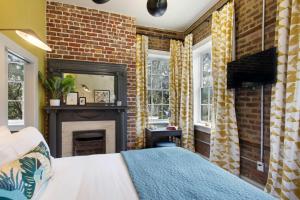 a bedroom with a brick wall and a fireplace at Sunny Queen Suite Downtown 2nd Floor in Savannah