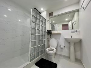 a white bathroom with a toilet and a sink at Kaza Living Usaquén in Bogotá