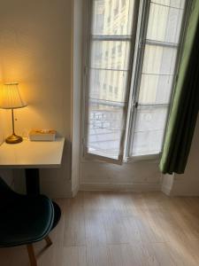 a room with a desk and a window with a lamp at Chez Bleu in Villejuif