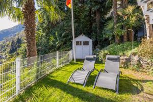 two chairs sitting in the grass next to a fence at Casa Samara in Cannobio