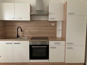 a kitchen with white cabinets and a stove top oven at Nice apartment in Celje in Celje