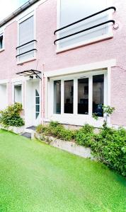 a pink house with a lawn in front of it at Maison design pour 8 pers proche Paris et Disney in Villiers-sur-Marne