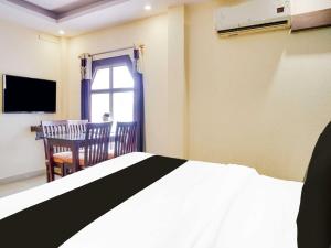 a bedroom with a bed and a chair and a television at Townhouse Oak Napier Town in Jabalpur +16 photos