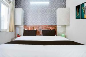 a bedroom with a white bed and a wall at Townhouse Oak Vasundra Nagar in Rajod +20 photos
