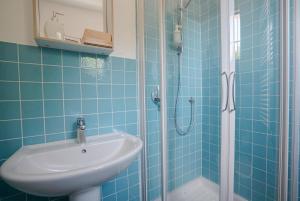 y baño de azulejos azules con lavabo y ducha. en Rifugio Cinque Terre, en Biassa