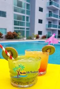 twee cocktails op een gele tafel naast een zwembad bij Maragogi-Peroba Ville Residence03 in Maragogi