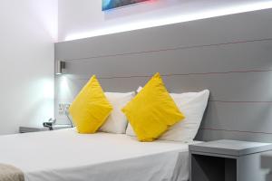 a bedroom with yellow pillows and a white bed at Ilford Hotel Goodmayes in Ilford