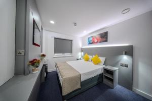 a small bedroom with a bed with yellow pillows at Ilford Hotel Goodmayes in Ilford