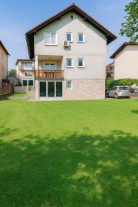 une maison avec une pelouse verte devant dans l'établissement Guesthouse Nestoria Living, à Banja Luka