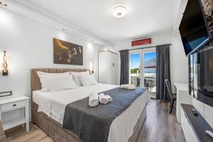 a bedroom with a bed with a television and a balcony at Apartments 1 with pool and private jacuzzi in Vodice +94 photos