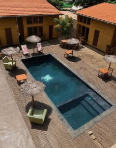 a swimming pool with umbrellas and chairs and tables at Toti guest house 3 in São Tomé