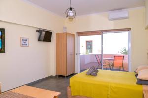 a bedroom with a yellow bed and a balcony at Callista sea view or garden in Kissamos