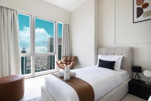 a bedroom with a bed and a chair and windows at Luxury 2BR Sea View Walk to Burj & Dubai Mall in Dubai