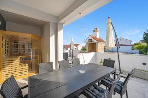 a wooden table on a balcony with chairs and an umbrella at Apartments 1 with pool and private jacuzzi in Vodice
