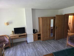 a living room with a tv and a desk with a computer at Ferienwohnung Allgäu Natur & Spa in Wiggensbach