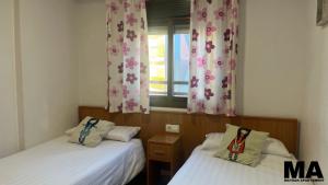 a room with two beds and a window with curtains at Maysan Apartamento in Benidorm +39 photos