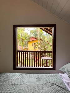 1 dormitorio con vistas a un balcón con cama en Casa Pindorama - Chalé Opy, en Paraty