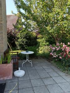 eine Terrasse mit einem Tisch, einer Bank und Blumen in der Unterkunft Michael, Vakantiehuisje aan zee in De Haan