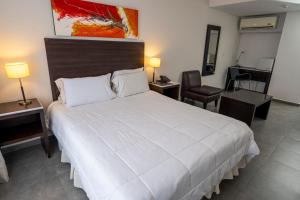 a bedroom with a large white bed and a chair at Hotel NEU 354 in Neuquén