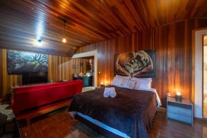 a bedroom with a red bed and a red couch at Recanto Lira 1 e 3 in Monte Verde