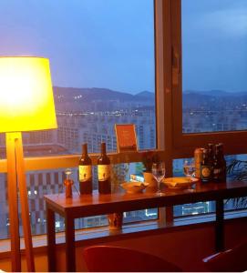 a table with wine bottles and glasses on a window at House on a high floor with beautiful sunsets in Gwangju
