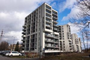 a tall white building with cars parked in a parking lot at Przestronny apartament PARKING by NEARTOpl in Kraków