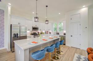 a kitchen with a large island with blue bar stools at HTX Modern Retreat with Rooftop Cinema in Houston