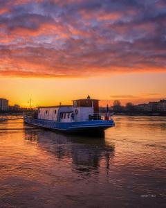 a boat sitting on the water at sunset at Péniche UHARTEA chambre d'hôtes "Baionako Gambara" in Bayonne