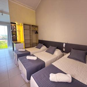 ein Hotelzimmer mit drei Betten und einem Laptop in der Unterkunft Hotel do Reinildo II in Cachoeira Paulista