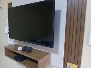 a flat screen tv on a wall with two remote controls at Hotel Padre Cícero in Lavras da Mangabeira