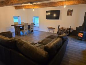 ein Wohnzimmer mit Ledersofa und einem Tisch in der Unterkunft Draugų sodyba in Trimputiškis