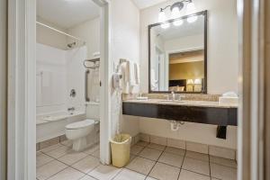 a bathroom with a sink and a toilet and a mirror at Coratel Plus Suites Wichita West Airport in Wichita +21 photos