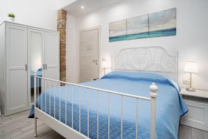 a bedroom with a white bed with a blue comforter at GARDEN HOUSE: APARTMENTS AND ROOMS FOR HOLIDAYS in Palermo