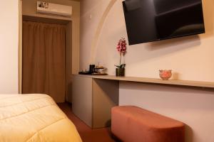 a room with a bed and a desk with a tv on the wall at Chiave di Volta luxury suite e rooms in Palermo