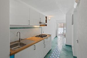 a white kitchen with a sink and a counter at B&B Residence Eco Del Mare in Palinuro