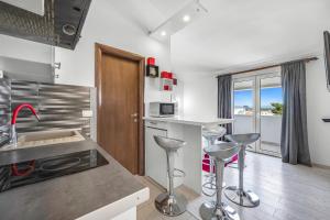a kitchen with a sink and a counter with stools at Apartments 2 with pool and private jacuzzi in Vodice