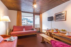 a living room with a red couch and a table at Résidence Pierre & Vacances Le Schuss in Val Thorens