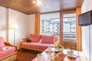 een woonkamer met een bank, een tafel en een raam bij Résidence Pierre & Vacances Le Schuss in Val Thorens