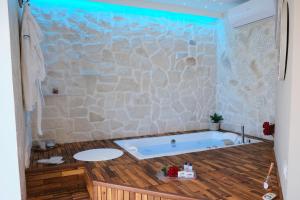 a bathroom with a tub with a stone wall at Pharus Miseni Suites and rooms in Bacoli