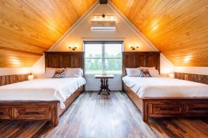 two beds in a room with wooden ceilings at Peletah Escape – Peaceful Bluegrass Getaway in Waddy