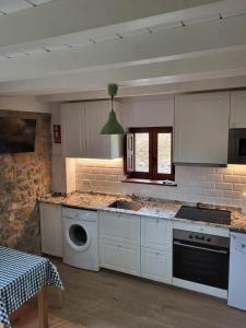 a kitchen with white cabinets and a sink and a dishwasher at Casa Liron in Corao