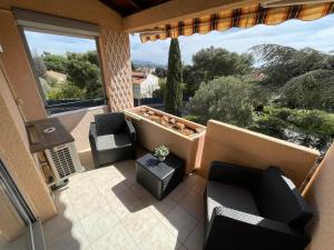 d'un balcon avec des canapés, des chaises et une grande fenêtre. dans l'établissement Agréable T2 climatisé, terrasse,wifi,piscine, à Bandol