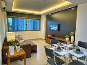 a living room with a couch and a table and chairs at Refúgio Manhattan Flat - Silencio, espaço e ao lado do shopping in Campo Grande