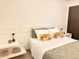 a white bedroom with a bed with two pillows at Refúgio Manhattan Flat - Silencio, espaço e ao lado do shopping in Campo Grande +13 photos