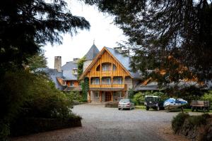 una casa grande con coches estacionados frente a ella en Hotel Tunquelén, en San Carlos de Bariloche