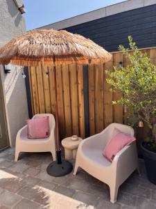 two chairs and an umbrella on a patio at Beachhouse Noteboom, omheinde tuin in Noordwijk aan Zee