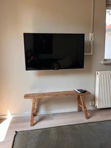 a living room with a wooden table with a tv on the wall at Beachhouse Noteboom, omheinde tuin in Noordwijk aan Zee