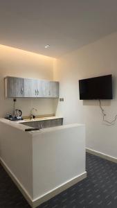 a kitchen with a counter and a tv on the wall at Madain Al Baraka Suites أجنحة مدائن البركة in Medina +15 photos