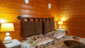 a bedroom with wooden walls and a bed with two lamps at Écolodge Les Sentiers du Lac - Domaine de la Gaïa in Sorèze +19 photos